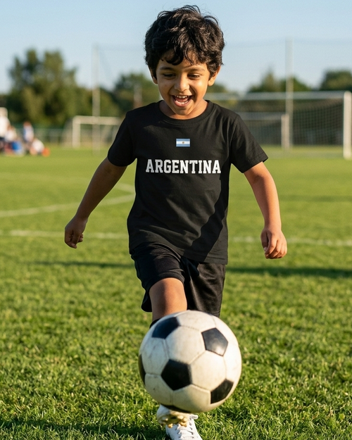 Child wearing a black  t-shirt with 'ARGENTINA' printed on it in a colourful outdoor playground.