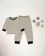 Black and white striped baby pajamas on a white background with star-shaped toys.