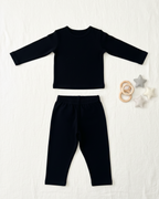 Black long-sleeve top and pants set on a white background with baby toys.