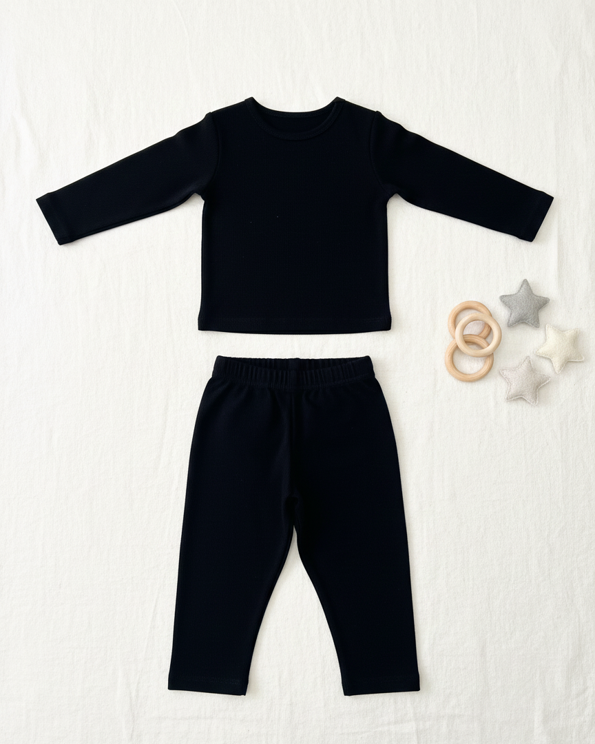 Black long-sleeve top and pants set on a white background with baby toys.