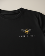 Black sweatshirt with a bee design and 'BEE KIND' text on a beige background
