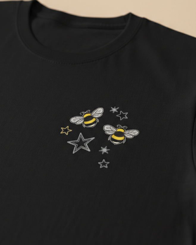 Black sweatshirt with bee and star embroidery on a beige background