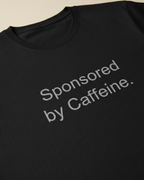 Black t-shirt with 'Sponsored by Caffeine' text on a beige background