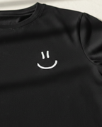 Black t-shirt with a white smiley face design on a light background