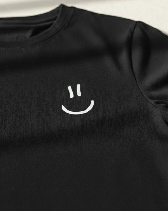 Black t-shirt with a white smiley face design on a light background