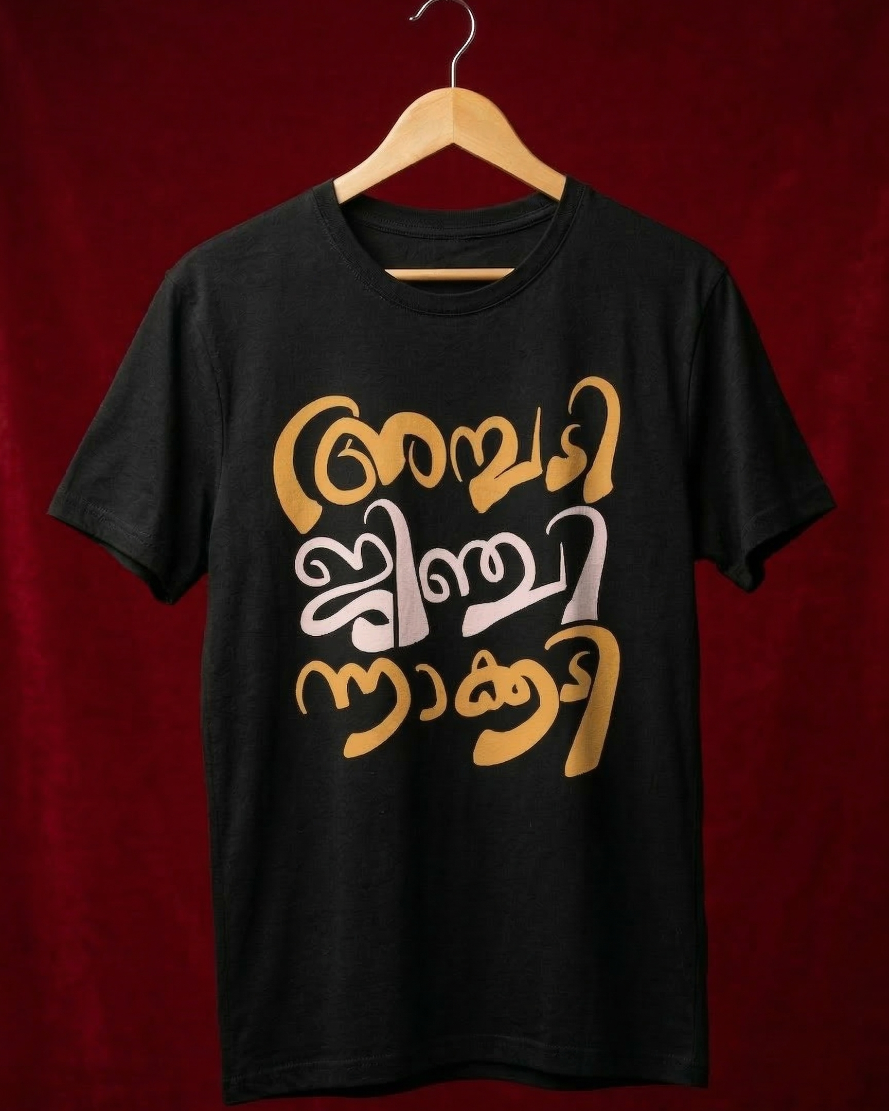 Black t-shirt with gold and white text on a wooden hanger against a red background