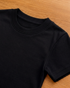 Black t shirt lie on grey background which focus of sleeve and neck part.