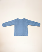 Blue grid-patterned long-sleeve shirt on a beige background