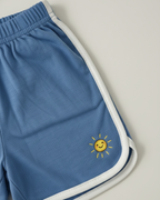 Blue shorts with a yellow sun design on a light gray background