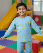 Child in a blue outfit with yellow patterns standing on colorful foam blocks in a playroom.