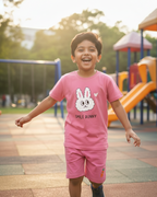 Child in a pink outfit with a bunny design on a playground