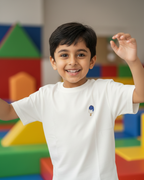Child in a white t-shirt with colorful geometric shapes in the background