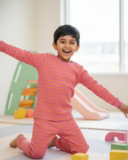Child in pink striped pajamas playing on a floor with colorful blocks
