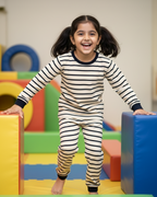 Child in striped pajamas standing on colorful foam blocks