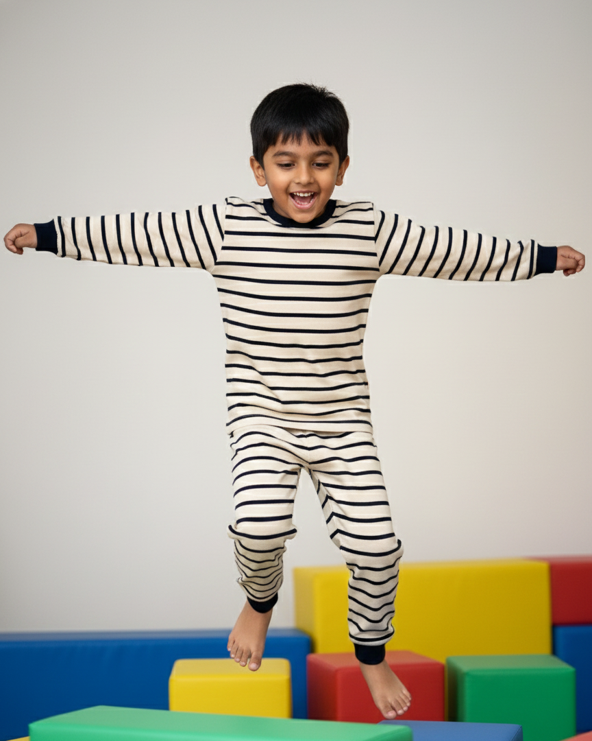 Child in striped pajamas standing on colorful foam blocks against a plain background