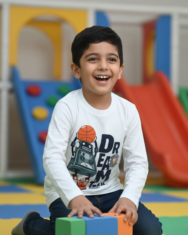 Child playing with colorful blocks in a playroom with slides and climbing structures.