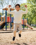 Child running on a playground with a colorful slide and equipment in the background