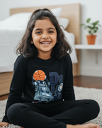 Child sitting on a carpeted floor wearing a black sweatshirt with graphics and text.
