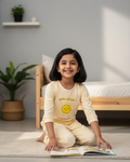 Child sitting on the floor with a book in a room with plants and a bed.