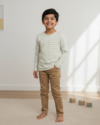 Child standing in a room with light-colored walls and wooden floor.