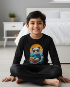 Child wearing a black long-sleeve shirt with a colorful panda design in a bedroom.