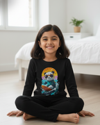 Child wearing a black long-sleeve shirt with a colorful panda design, sitting on the floor in a bright room.