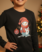Child wearing a black long-sleeve shirt with a snowman design in front of a decorated Christmas tree.