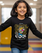 Child wearing a black long-sleeve shirt with colorful graphics and text in an indoor setting.