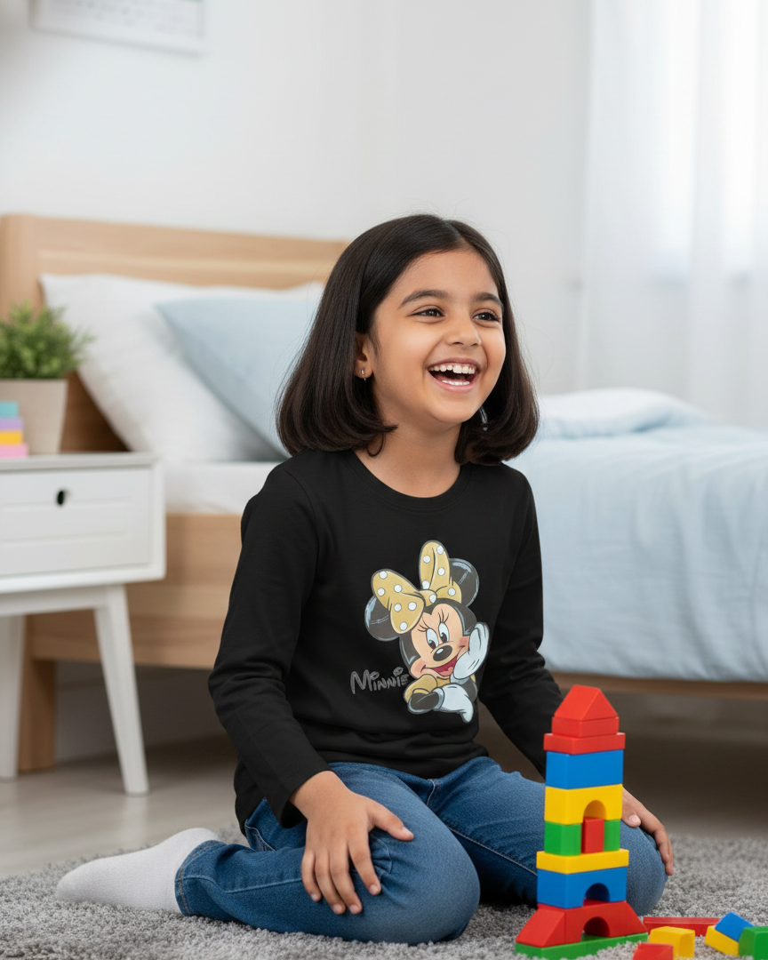 Child wearing a black shirt with a cartoon character, sitting on the floor with building blocks in a bedroom.