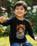 Child wearing a black shirt with a character design, sitting outdoors with flowers and butterflies.