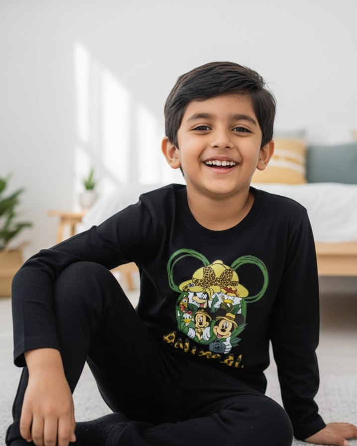 Child wearing a black shirt with a graphic design sitting on the floor in a room.