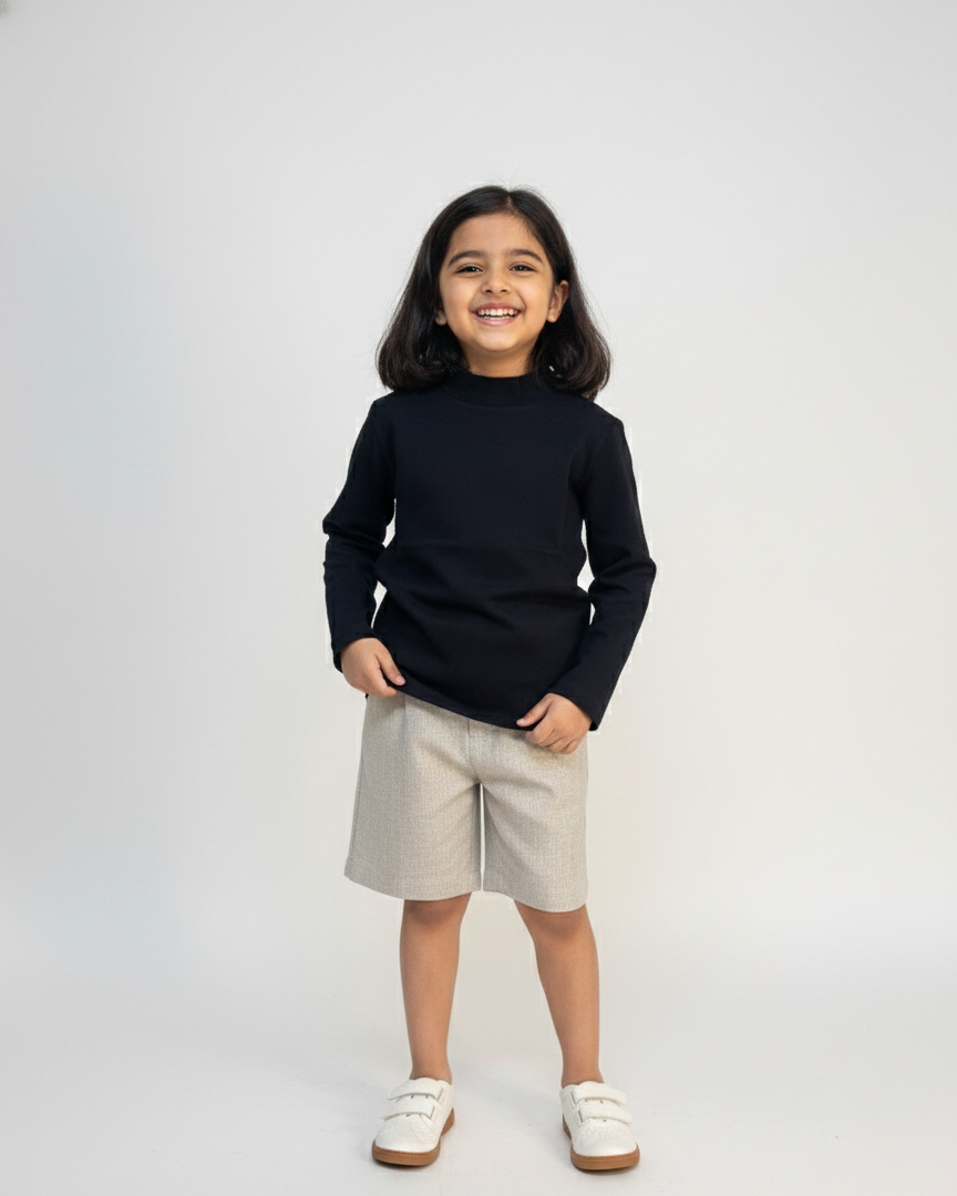 Child wearing a black sweater and beige shorts on a white background