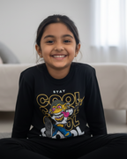 Child wearing a black sweatshirt with colorful graphics sitting on the floor in a room.