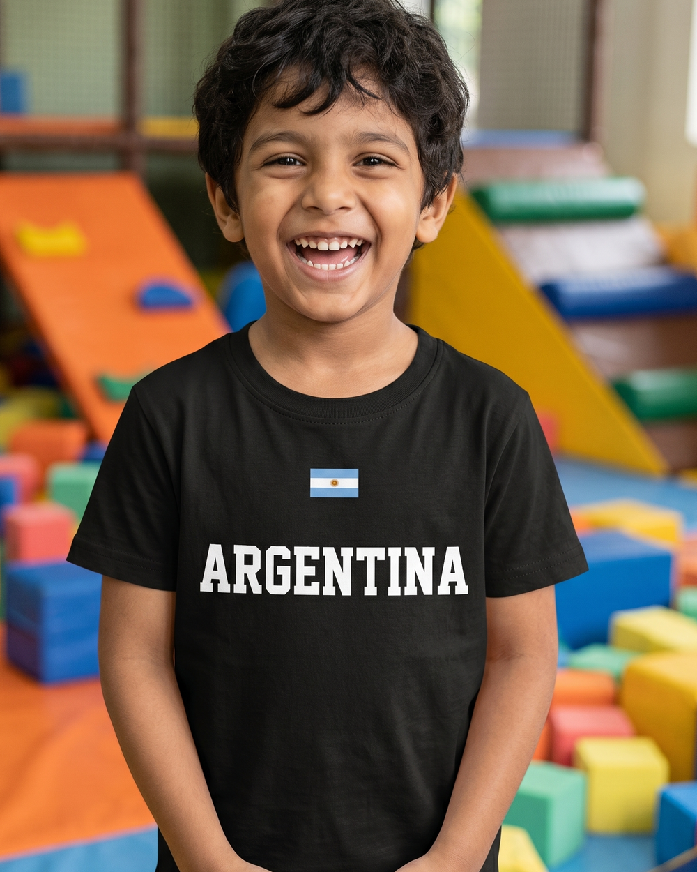 Child wearing a black t-shirt with 'ARGENTINA' printed on it in a colorful indoor playground.