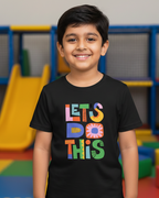 Child wearing a black t-shirt with colorful text in an indoor playground setting