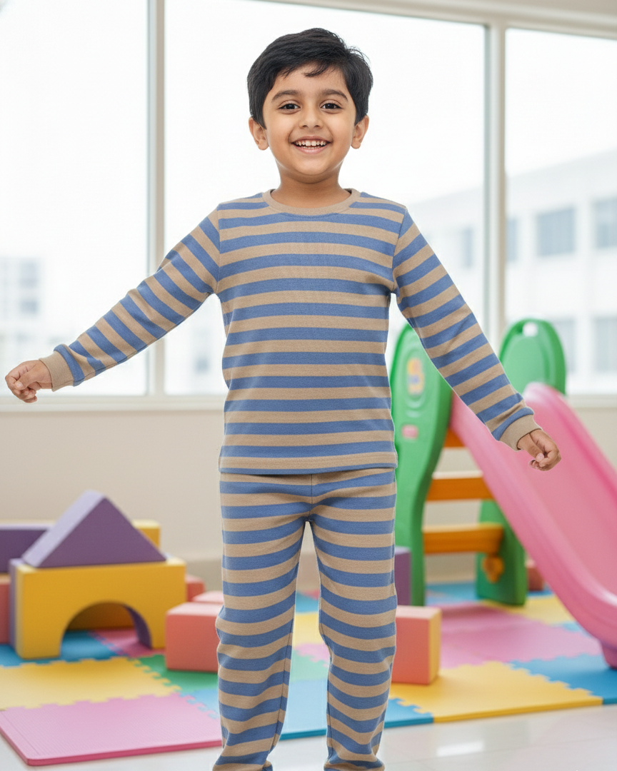 Child wearing a blue and brown striped pajama set in a playroom.