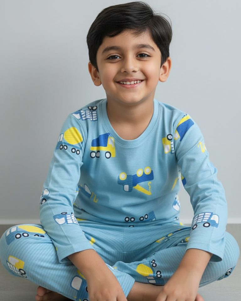 Child wearing a blue pajama set with vehicle patterns on a gray background