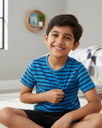 Child wearing a blue striped shirt sitting on a bed in a bedroom.