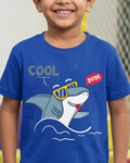 Child wearing a blue t-shirt with a shark graphic and text in a colorful indoor setting
