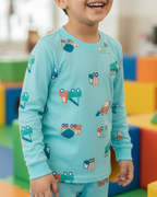Child wearing a light blue pajama set with vehicle patterns in a colorful indoor setting.