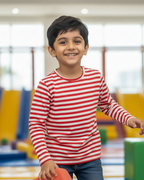Child wearing a red and white striped shirt in an indoor playground.