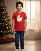 Child wearing a red t-shirt with a graphic design, standing in front of a decorated Christmas tree.