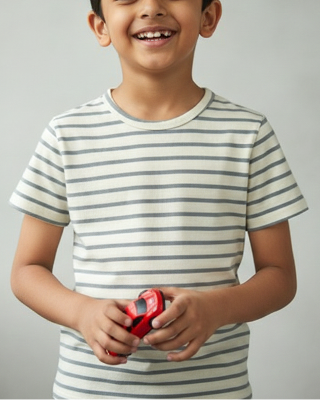 Child wearing a striped shirt holding a red object against a gray background