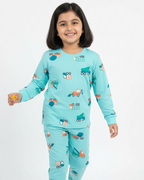 Child wearing a turquoise pajama set with vehicle prints on a white background