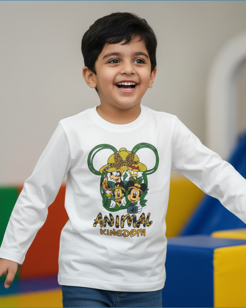Child wearing a white long-sleeve shirt with 'Animal Kingdom' design, standing in a colorful indoor setting.