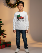Child wearing a white long-sleeve shirt with a Christmas design, standing in front of a decorated Christmas tree and presents