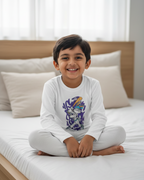 Child wearing a white long-sleeve shirt with a graphic design in a minimalist bedroom background
