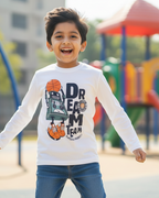 Child wearing a white long-sleeve shirt with graphics and text on a playground background