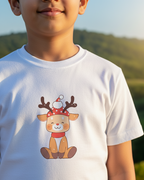 Child wearing a white t-shirt with a cartoon reindeer design outdoors.