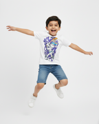 Child wearing a white t-shirt with a colorful graphic design, blue shorts, and white shoes on a light gray background